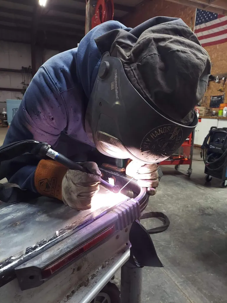 Precision welding with American flag backdrop at McMahons shop